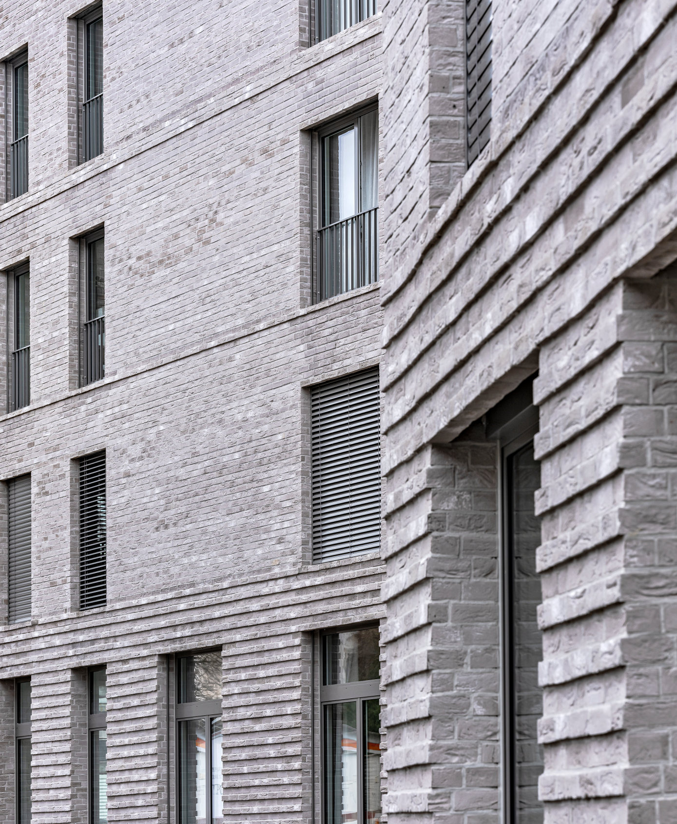 Moderne Fassade aus grauem Backstein mit mehreren Fenstern