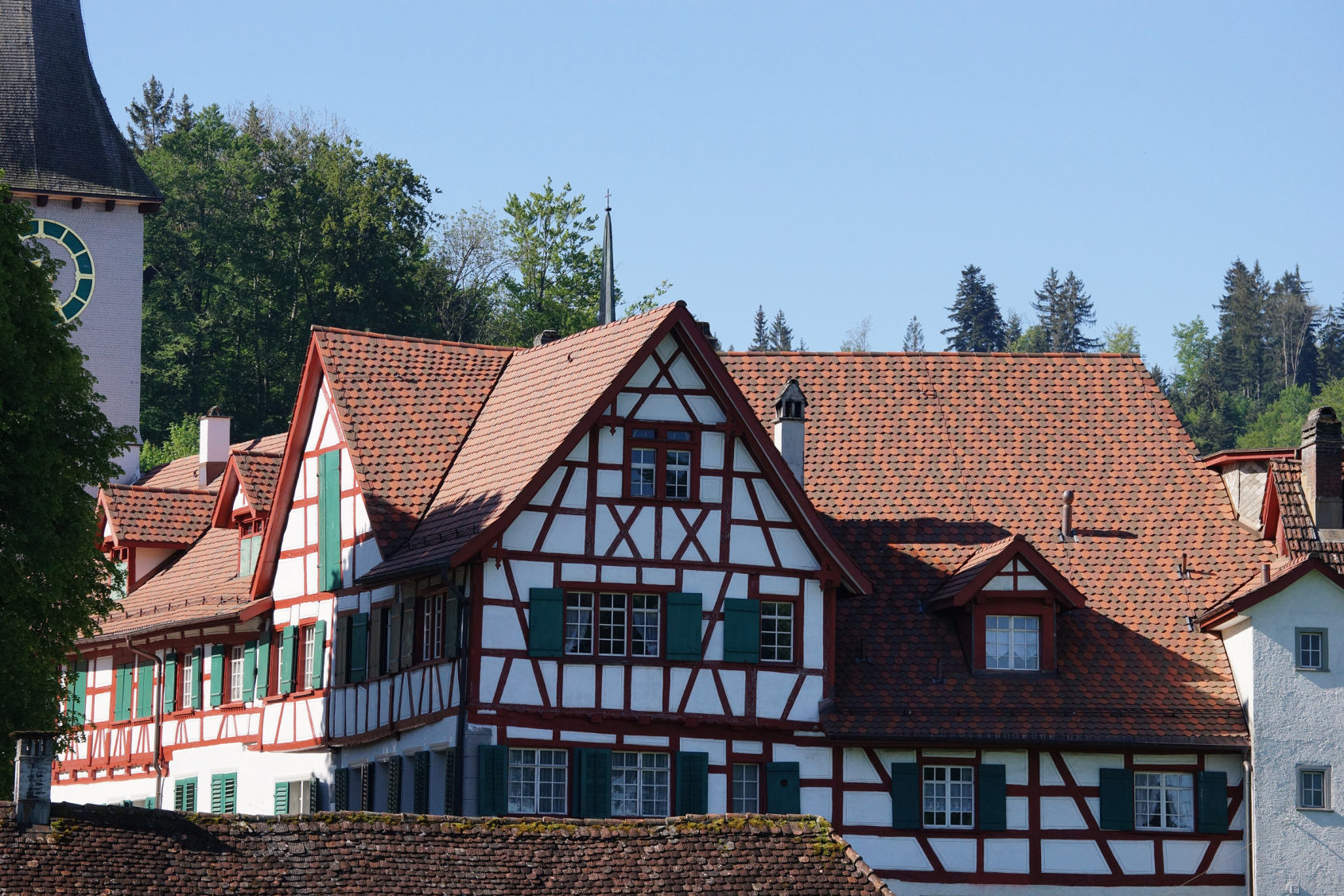 Fachwerkhaus mit roten Dachziegeln und gruener Umgebung bei Sonnenschein